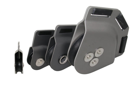 Vier SEA SURE Schothornblöcke SS0487, SS0488, SS0490 und SS0492 aus anthrazit eloxiertem Aluminium in unterschiedlichen Größen, mit dunklen Rollen und Gurtbandschlitzen, Seitenansicht und schräge Ansichten vor weißem Hintergrund.
